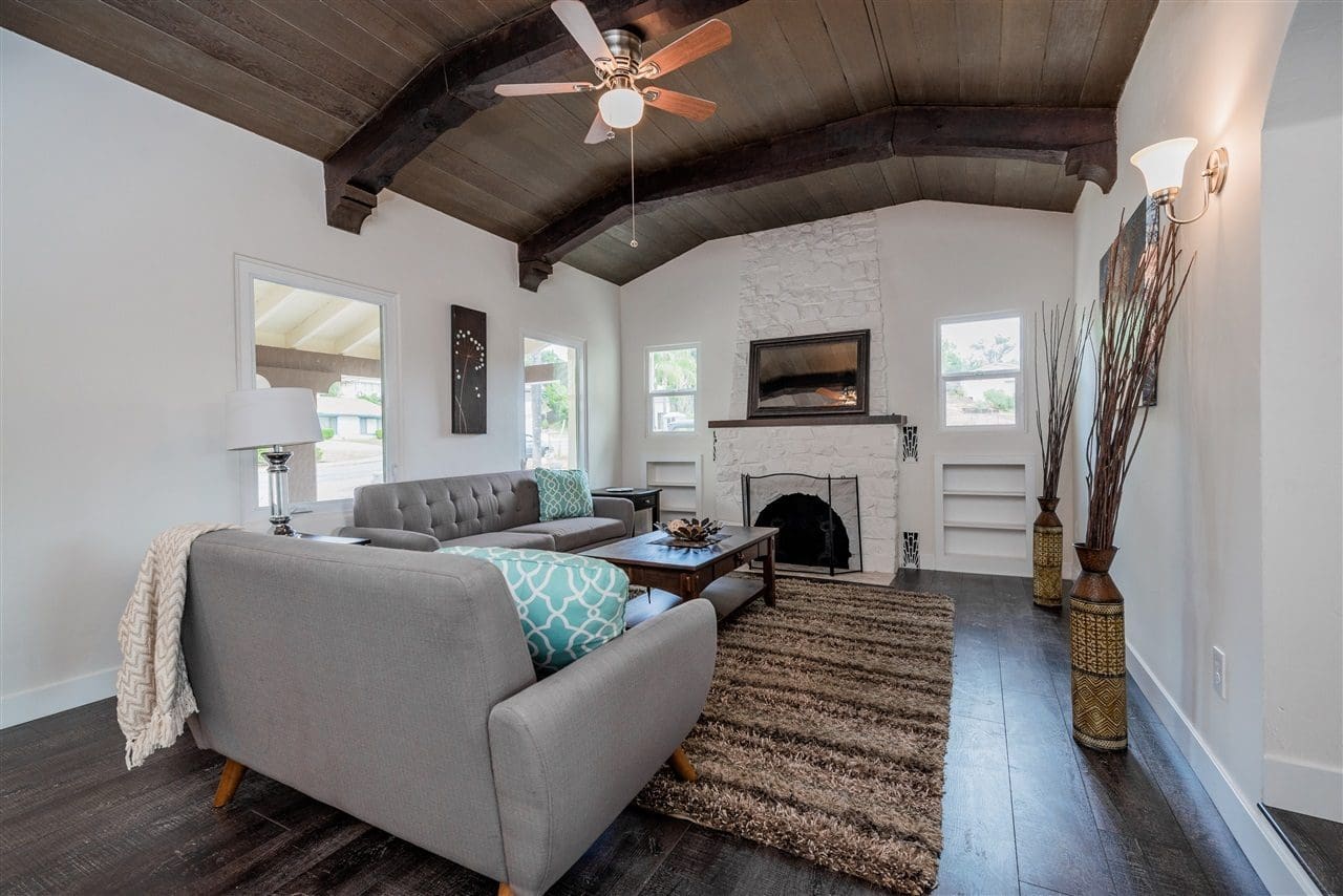 A living room with a couch, fireplace and ceiling fan.