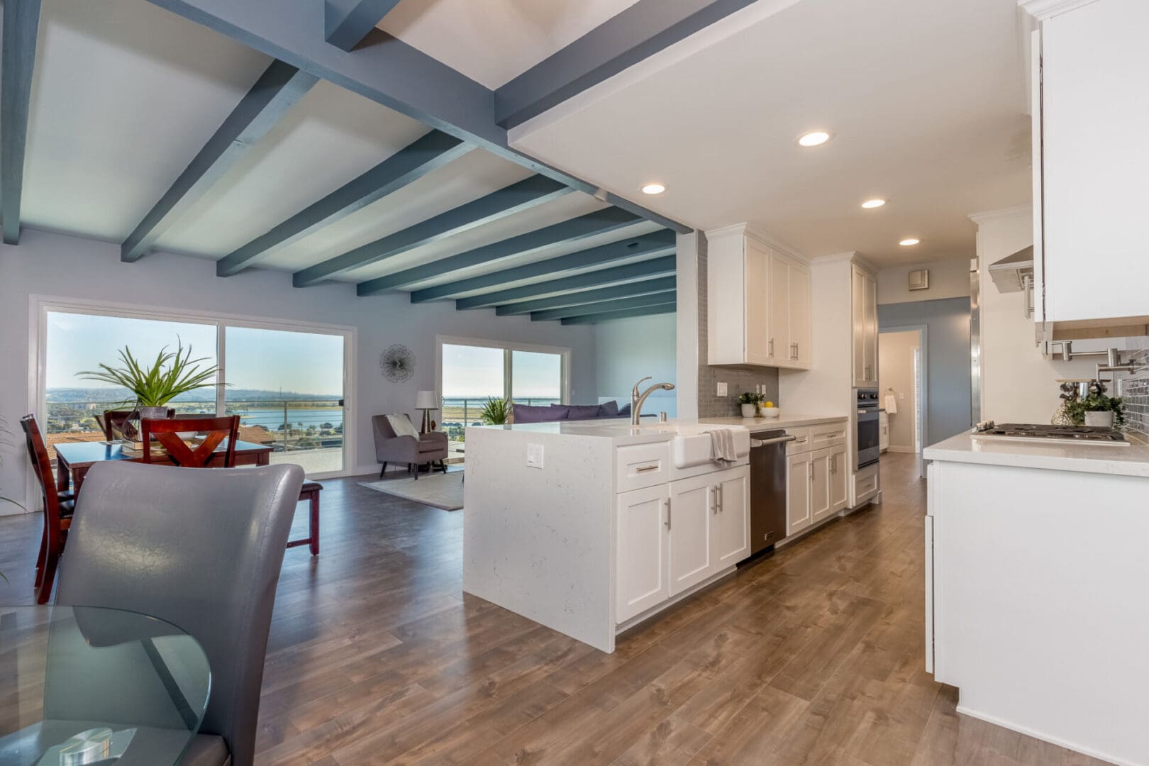 A kitchen with white cabinets and wooden floors.