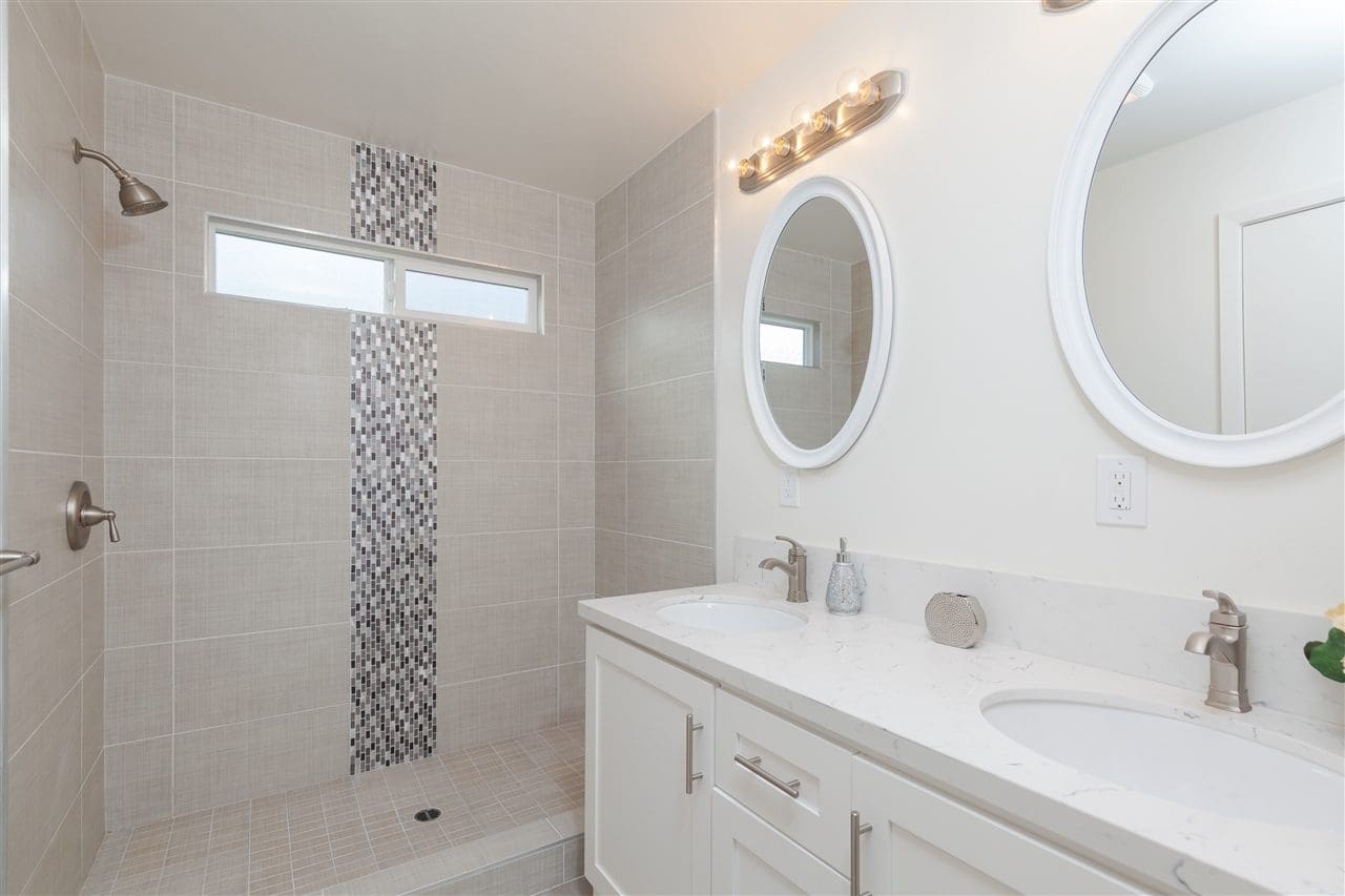 A bathroom with two sinks and a shower.