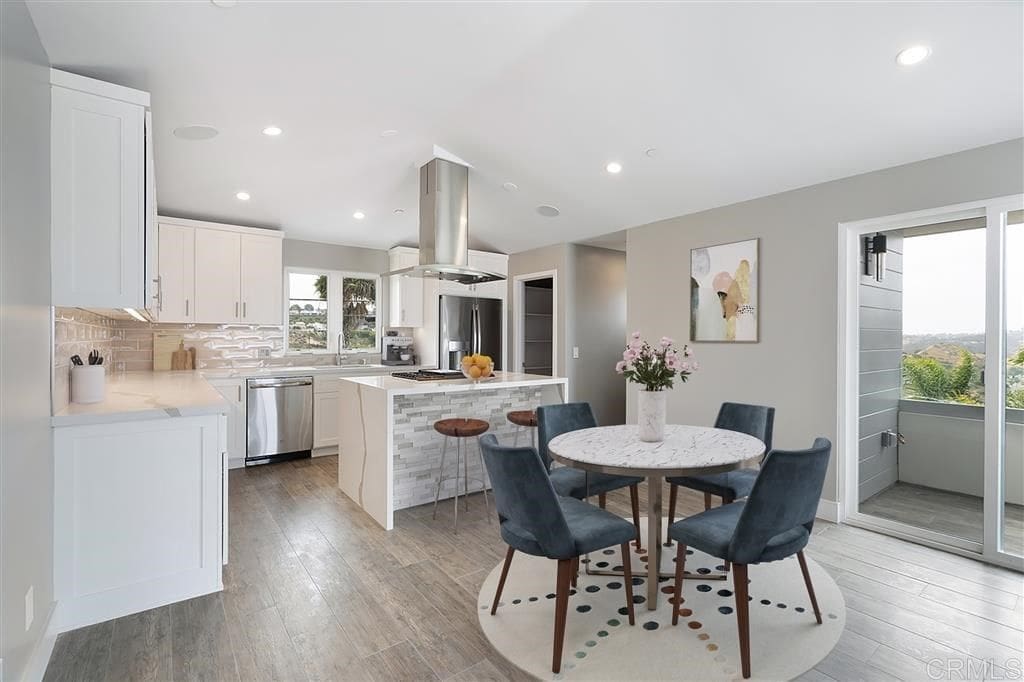 A kitchen with white cabinets and wooden floors.