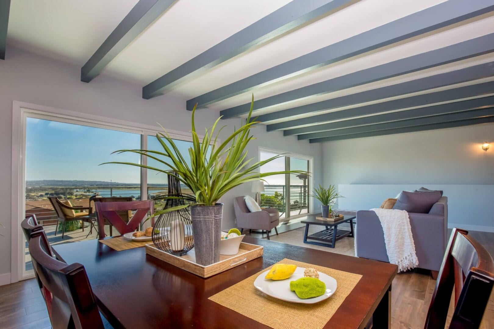 A living room with a table and chairs, potted plant on the side of the floor.